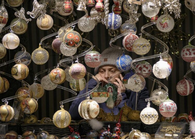 A vendor speaks on the phone at a Christmas market in Vienna, Austria, yesterday. The Austrian government announced a nationwide lockdown that will start Monday and comes as average daily deaths have tripled in recent weeks and hospitals in heavily hit states have warned that intensive care units are reaching capacity.