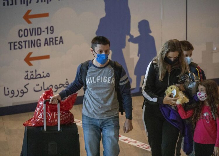 Israel tightens travel restrictions over new COVID variant 1 - Egyptian Gazette Travelers wearing protective face masks arrive at the Ben Gurion Airport near Tel Aviv, Israel, yesterday. Israel yesterday approved barring entry to foreign nationals and the use of controversial technology for contact tracing as part of its efforts to clamp down on a new coronavirus variant.