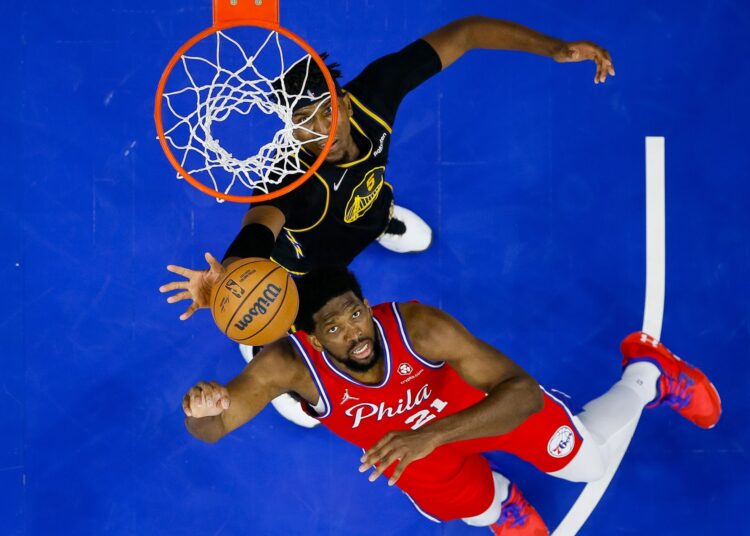 Philadelphia 76ers' Joel Embiid (R) shoots while being guarded by Golden State Warriors' Kevon Looney during their NBA game in Philadelphia.