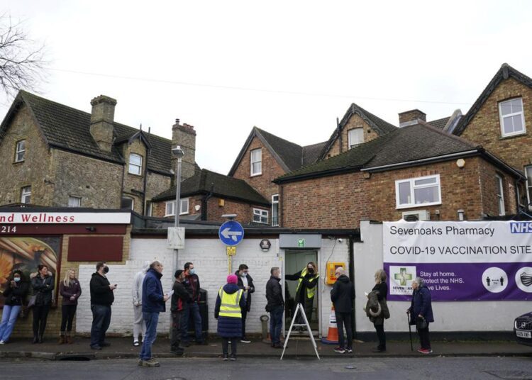 People queue for booster jabs at Sevenoaks Pharmacy in Sevenoaks, England, Monday, Dec. 13, 2021. Britain's Prime Minister Boris Johnson says that Britain faces a "tidal wave" of infections from the omicron coronavirus variant and he has announced a huge increase in booster vaccinations to strengthen defenses against it.