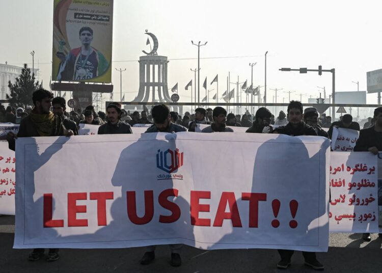 People hold a banner reading ‘Let us eat’ before marching on the street during a protest in Kabul on December 21, 2021, as the country struggles with a deep economic crisis.