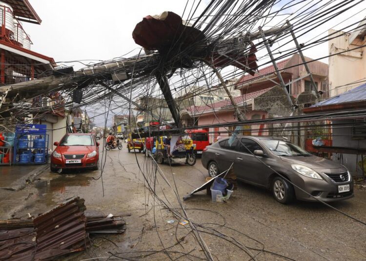 A file photo of cars passing by a toppled electrical post due to Typhoon Rai in Surigao city, Surigao del Norte, southern Philippines.