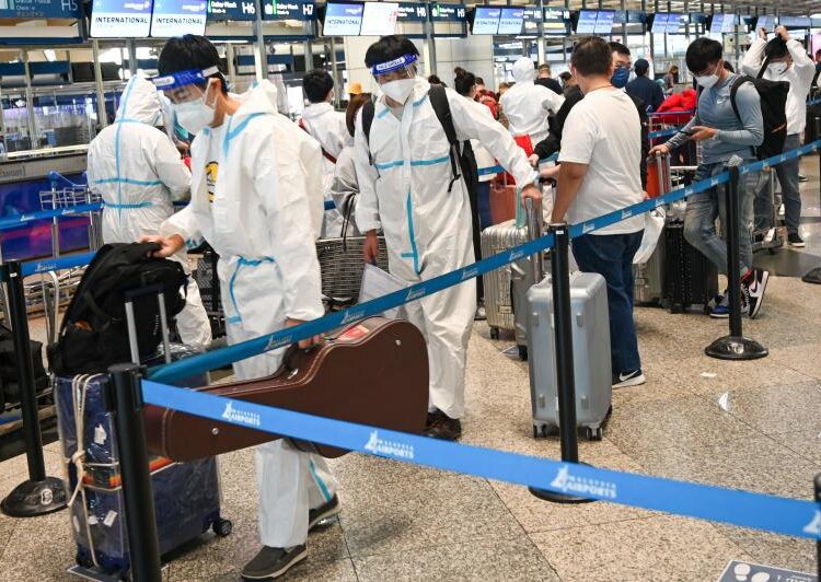 Passengers wearing personal protective equipment queue to check-in for their flight at the Kuala Lumpur International Airport in Sepang on December 1, 2021.
