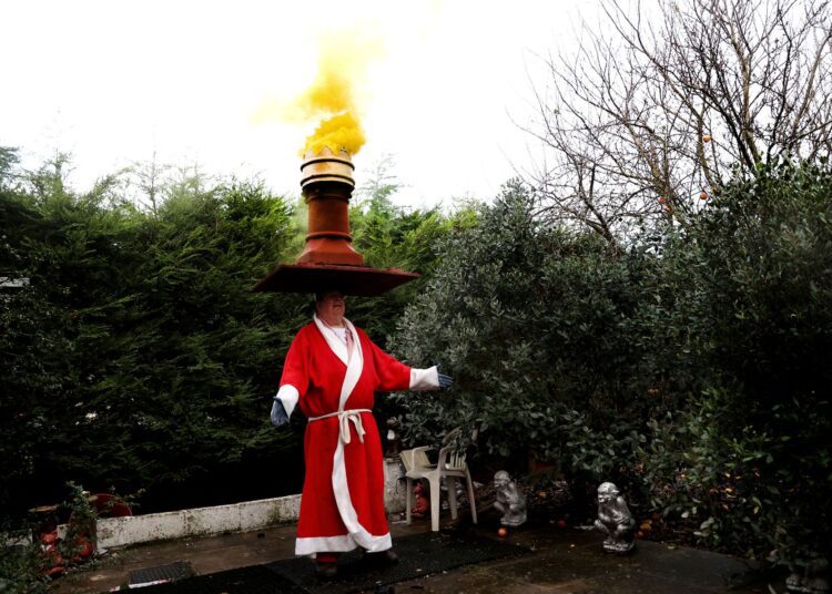 John Evans balances a chimney on his head, in Ilkeston, Britain, December 8, 2021.