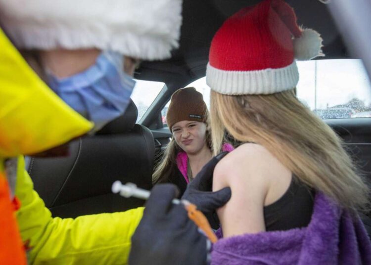 Canada´s Ontario limits capacity at restaurants at 50% 1 - Egyptian Gazette Little sister Korie Smith, 8, looks on as big sister Mattie Smith, 10, receives her vaccine during a drive-thru Covid-19 vaccine clinic at St. Lawrence College in Kingston, Ontario on Dec. 4, 2021.