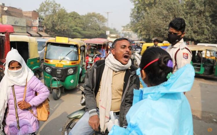 A healthcare worker collects a COVID-19 test swab sample from a man on a road in New Delhi, India, Dec 6, 2021.