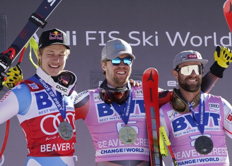 Norway's Aleksander Aamodt Kilde (C) celebrates a first place finish while posing beside second-place finisher Switzerland's Marco Odermatt (L) and third-place finisher United States' Travis Ganong after a men's World Cup super-G skiing race in Beaver Creek, Colo.