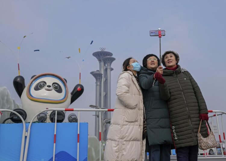 Beijing residents disappointed Olympics will be closed event 1 - Egyptian Gazette A woman wearing a face mask to help protect from the coronavirus takes a selfie with her companion against a Beijing Winter Olympics Mascot and Olympic Tower in Beijing, Wednesday, Jan. 19, 2022. China has locked down parts of Beijing's Haidian district following the detection of three cases, just weeks before the capital is to host the Winter Olympic Games.