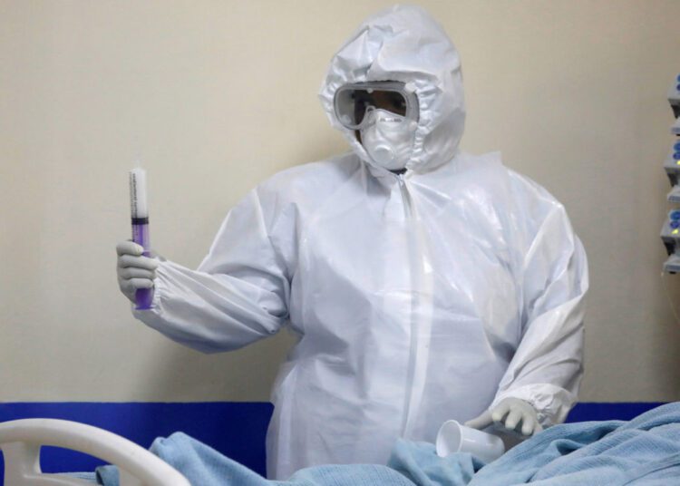 FILE PHOTO: A member of the medical staff dressed in a protective suit holds a syringe as he treats a coronavirus disease patient inside the COVID-19 ICU of Machakos Level 5 Hospital, in Machakos, Kenya October 28, 2020. Picture taken October 28, 2020. REUTERS/Baz Ratner/File Photo