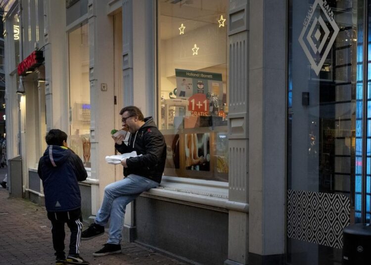 Closed restaurants because of a lockdown forced people to eat outdoors next to a closed shop in Amsterdam, Netherlands, on Dec. 30, 2021, as the fast-spreading coronavirus variant omicron rages through Western Europe.
