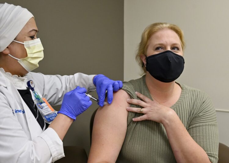 A file photo shows a nurse administers a Pfizer COVID-19 booster shot to a woman in California.