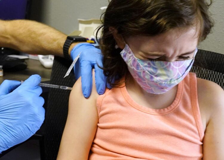 McKenna Brown, 10, turns her head away as she receives a Pfizer COVID-19 vaccine at Pucci's Pharmacy in Sacramento, Calif., on Jan. 25, 2022.