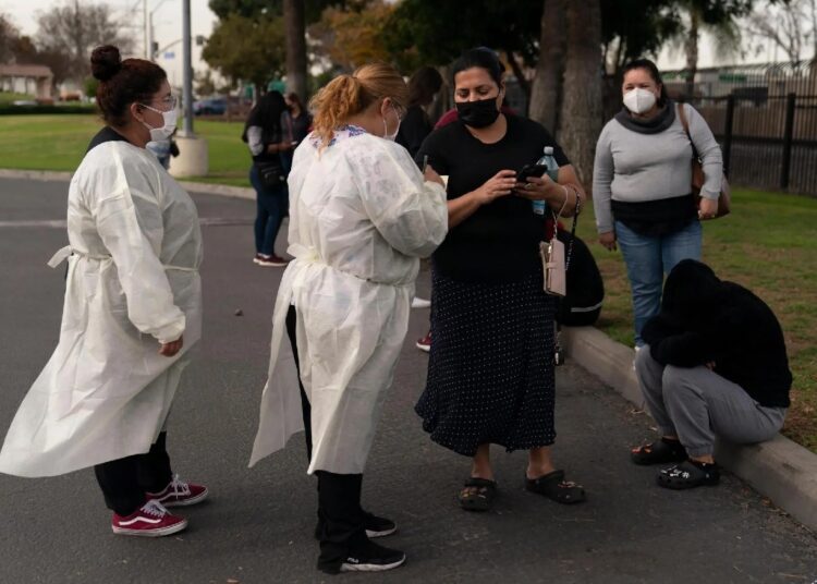 Two healthcare workers help residents check in at a mobile COVID-19 testing site in Paramount, Calif., on Jan. 12, 2022.