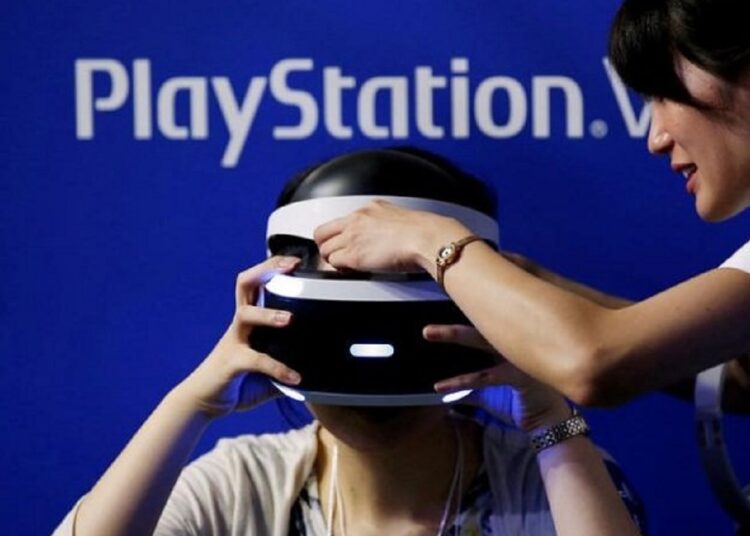 Sony teases details of next-gen VR headset 1 - Egyptian Gazette A hostess helps a woman to wear Sony's PlayStation VR headset at Tokyo Game Show.