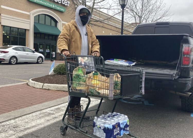 Chris Stokes picks up extra provisions at a grocery store in Norfolk, Va., on Jan. 21, 2022, as the city prepares for an upcoming snowstorm.