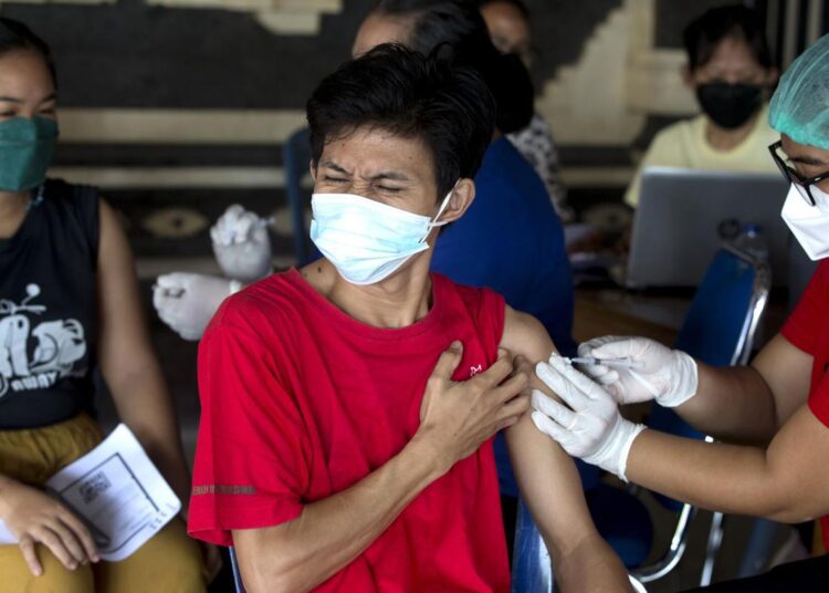 A man reacts as he received a Moderna COVID-19 booster shot during a third dose vaccination campaign in Denpasar, Bali, Indonesia on Saturday, Jan. 29, 2022.