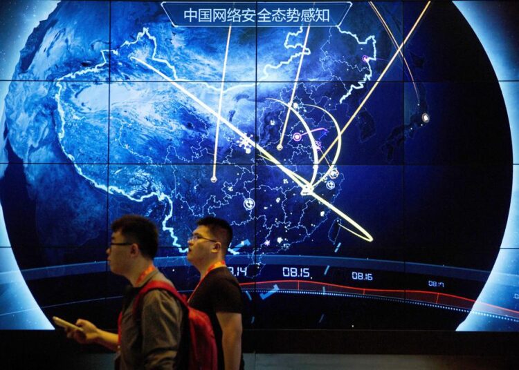 FILE - In this Sept. 12, 2017, file photo, attendees walk past an electronic display showing recent cyberattacks in China at the China Internet Security Conference in Beijing. Cybersecurity and space are emerging risks to the global economy, adding to existing challenges posed by climate change and the coronavirus pandemic, the World Economic Forum said in a report Tuesday, Jan. 11, 2022.