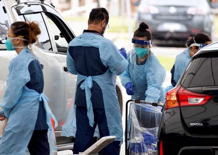 Australia’s daily Covid-19 infections dip below 100,000 1 - Egyptian Gazette Healthcare workers administer Covid-19 tests at St Vincent's Hospital drive-through testing clinic at Bondi Beach in Sydney, December 17, 2021.