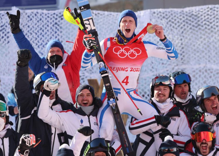Gold medallist France's Clement Noel (C top) celebrates with his team after the men's slalom victory ceremony at the Beijing 2022 Winter Olympic Games at the Yanqing National Alpine Skiing Centre in Yanqing on February 16, 2022. (Photo by Dimitar DILKOFF / AFP)