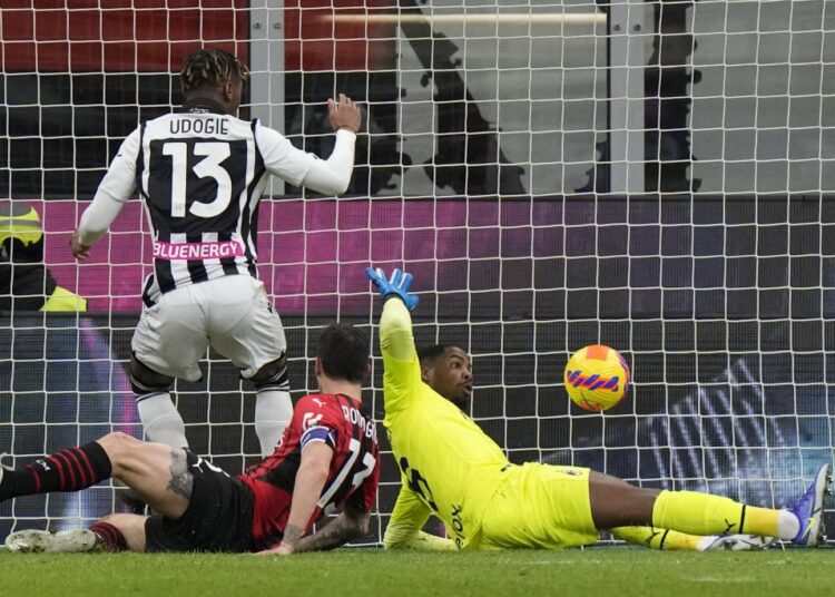 Udinese's Destiny Udogie (L) scores his side's opening goal during a Serie A match between AC Milan and Udinese, in Milan, Italy.