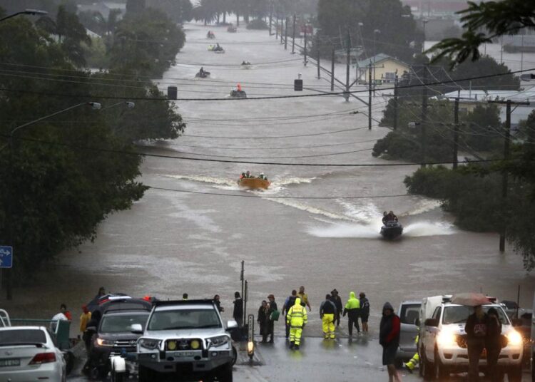 People use small boats to travel through flood water in Lismore, Australia, Monday, Feb. 28, 2022. Heavy rain is bringing record flooding to some east coast areas and claimed seven lives while the flooding in Brisbane, a population of 2.6 million, and its surrounds is the worst since 2011 when the city was inundated by what was described as a once-in-a-century event.