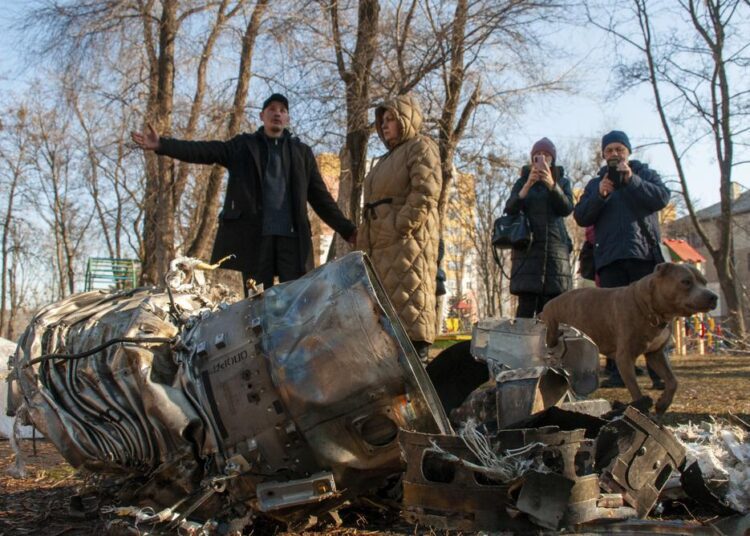 Russia attacks Ukraine as defiant Putin warns US, NATO 1 - Egyptian Gazette People stand next to fragments of military equipment on the street in the aftermath of an apparent Russian strike in Kharkiv in Kharkiv, Ukraine, Thursday. Russian troops have launched their anticipated attack on Ukraine. Big explosions were heard before dawn in Kyiv, Kharkiv and Odesa as world leaders decried the start of an Russian invasion that could cause massive casualties and topple Ukraine's democratically elected government.
