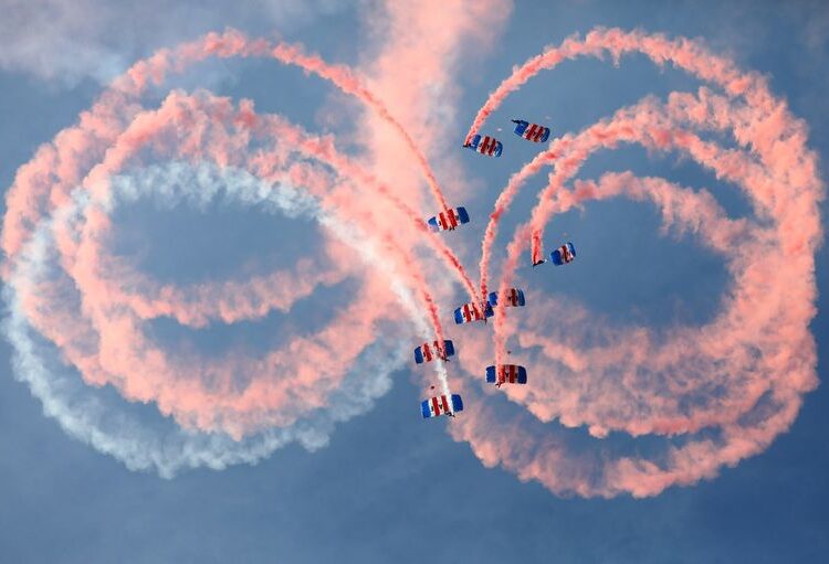 An RAF parachute display team let off smoke canisters as they descend as part of a ceremony for the Queen's Baton Relay for the 2018 Gold Coast Commonwealth Games at Brize Norton, Britain August 16, 2017. REUTERS/Neil Hall