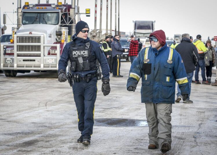 Canada PM: military response not in cards for Covid protests 1 - Egyptian Gazette An officer talks with an anti-Covid19 vaccine mandate demonstrator at road block on the highway in Milk River, Alta., on Feb. 3, 2022.