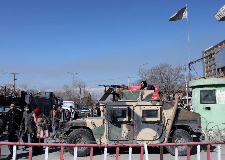 UN has millions in Afghanistan bank, but cannot use it 1 - Egyptian Gazette Afghans walk past a Humvee with a Taliban fighter on it guarding the road in Kabul, Afghanistan, on January 27, 2022.