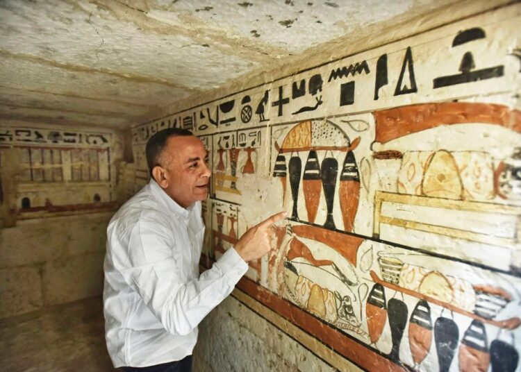 Mostafa Waziri, Secretary General of the Supreme Council of Antiquities, views hieroglyphics inside a recently discovered tomb near the famed Step Pyramid, in Saqqara, south of Cairo, Egypt, Saturday, March 19, 2022.