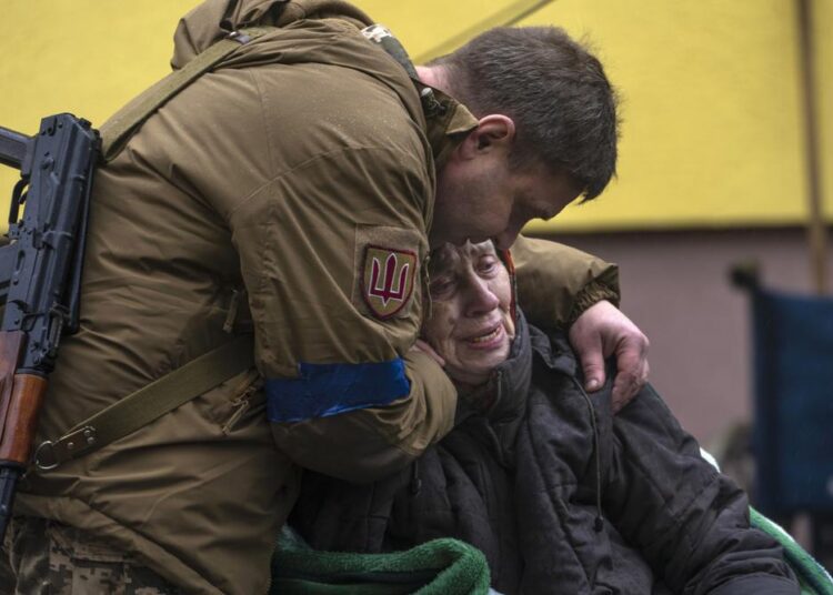 A soldier comforts Larysa Kolesnyk, 82, after she was evacuated from Irpin, on the outskirts of Kyiv, Ukraine, yesterday.
