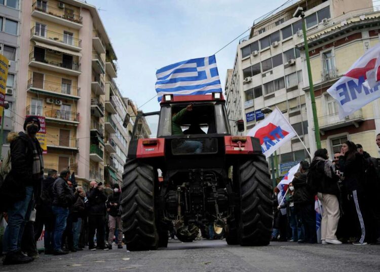 A farmer sits on a tractor with a Greek flag during a protest outside of the Agriculture Ministry in Athens, Greece, on March 18, 2022.