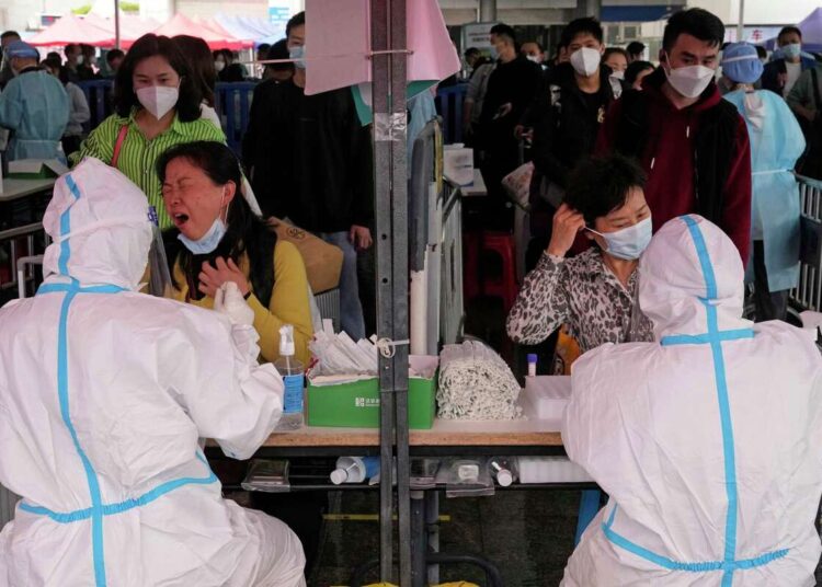 China continues 'severe and complex' fight against COVID-19 1 - Egyptian Gazette A woman reacts to having a sample taken for a COVID-19 test at the Guangzhou train station on Friday, March 25, 2022, in southern China's Guangzhou province.