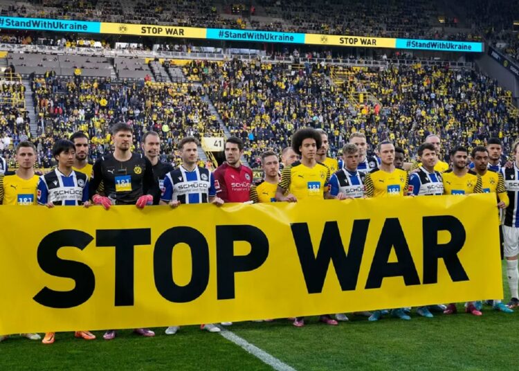 Players holding a banner to protest against Russia's war in Ukraine prior the German Bundesliga match between Borussia Dortmund and Arminia Bielefeld in Dortmund, on March 13, 2022.