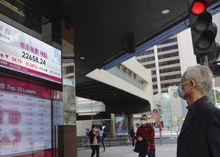 A man looks at a bank's electronic board showing the Hong Kong share index at Hong Kong Stock Exchange on Tuesday, March 1, 2022.