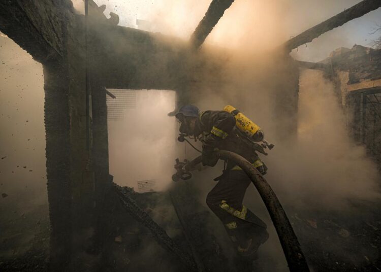 A Ukrainian firefighter sprays water inside a house destroyed by shelling in Kyiv, Ukraine, on Wednesday, March 23, 2022.