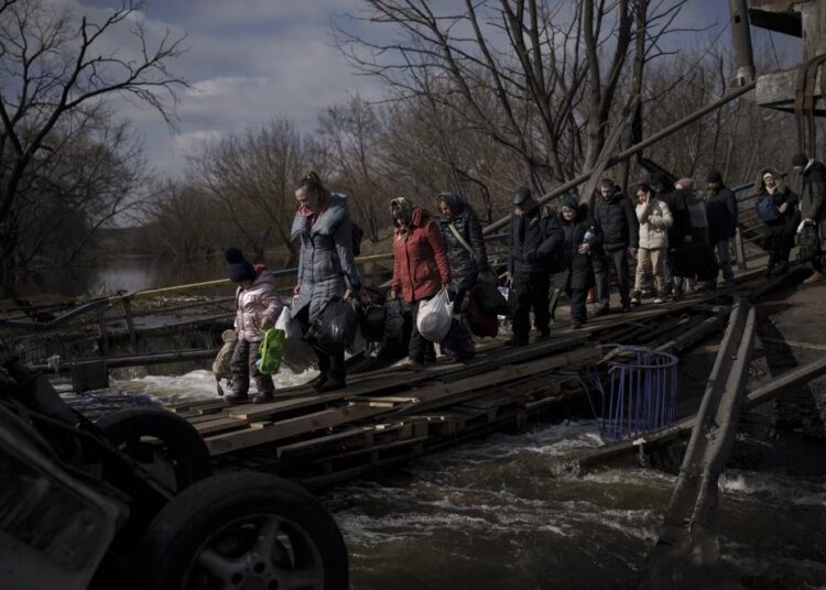 Ukrainians cross an improvised path under a destroyed bridge while fleeing Irpin, on the outskirts of Kyiv, Ukraine, Wednesday, on March 9, 2022.