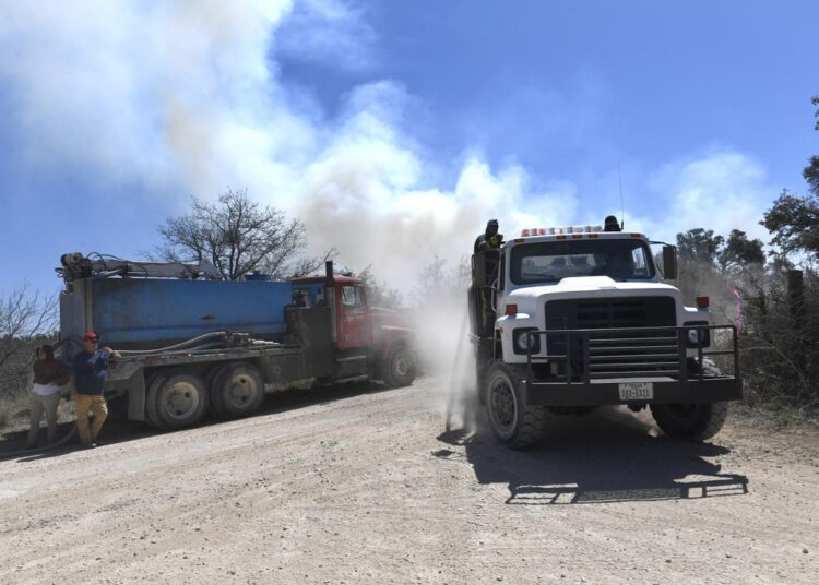 Members of the Carbon Volunteer Fire Department pass through a rural Eastland County, Texas, intersection while fighting the Kidd Fire, Saturday, March 19, 2022.