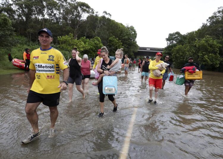 People wade through flood water as they relocate in Chinderah, Australia, Tuesday, March 1, 2022.