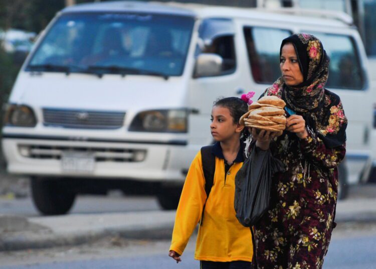 FILE PHOTO: A woman carrying bread walks her daughter to school in the Giza suburb of Awsim, Egypt October 10, 2021. REUTERS/Shokry Hussien