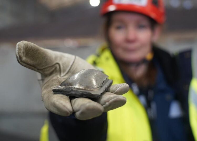 Susanne Rostmark, research leader, LKAB, holds a piece of hot briquetted iron ore made using the HYBRIT process nearby the venture’s pilot plant in Lulea, Sweden on Feb. 17, 2022. The steel-making industry is coming under increasing pressure to curb its environmental impact and contribute to the Paris climate accord, which aims to cap global warming at 1.5 degrees Celsius.