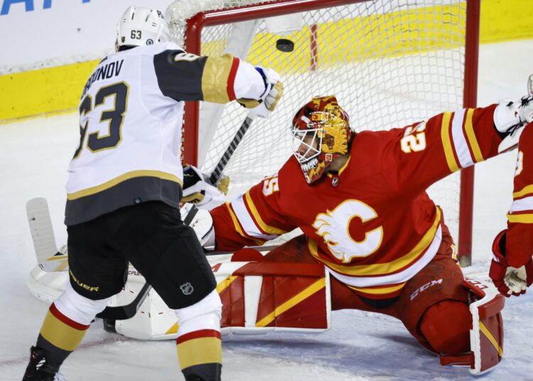 Vegas Golden Knights' Evgenii Dadonov (L) scores against Calgary Flames goalie Jacob Markstrom during their NHL game in Calgary.