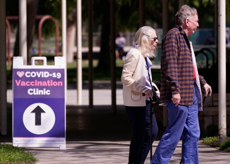 People leave a testing and vaccination clinic for COVID-19, March 30, 2022, in Long Beach, Calif.