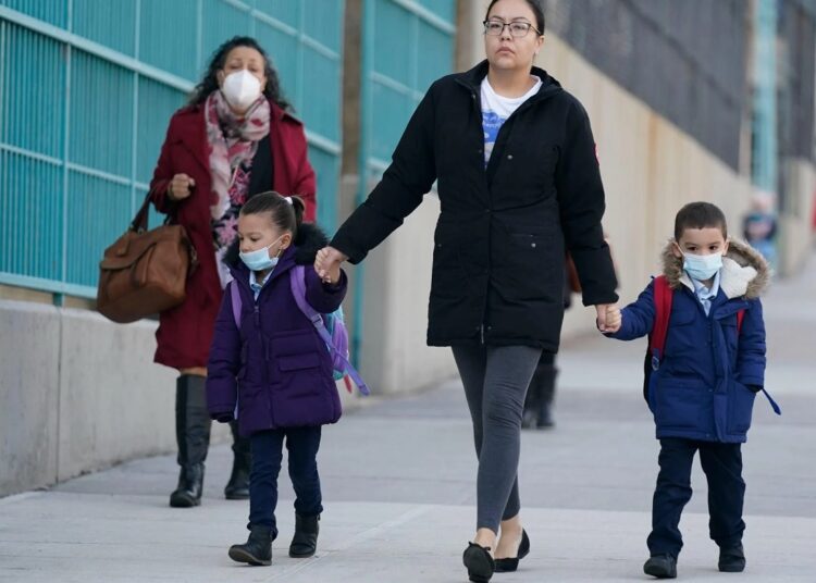 A file photo shows children and their caregivers arrive for school in New York on March 7, 2022.