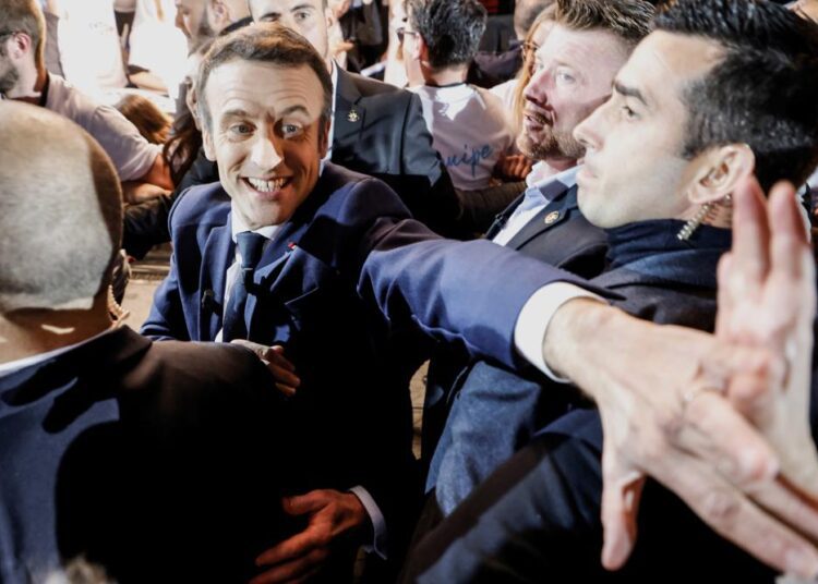 French President Emmanuel Macron and centrist candidate for reelection shakes hands with supporters as he arrives for a meeting in Paris, on April 2, 2022.