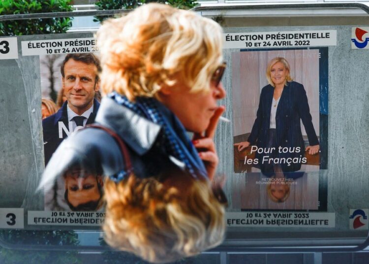 Macron, Le Pen face off in crucial election debate 1 - Egyptian Gazette A woman walking past official campaign posters of French presidential election candidates Marine le Pen, leader of French far-right National Rally (Rassemblement National) party, and French President Emmanuel Macron, candidate for his re-election, displayed on an official billboard in Paris.