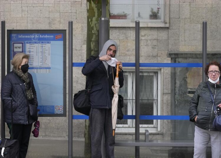 A man puts on his mask to protect against the spread of Covid-19 before boarding a bus in Madrid, Spain, on Wednesday, April 20, 2022.
