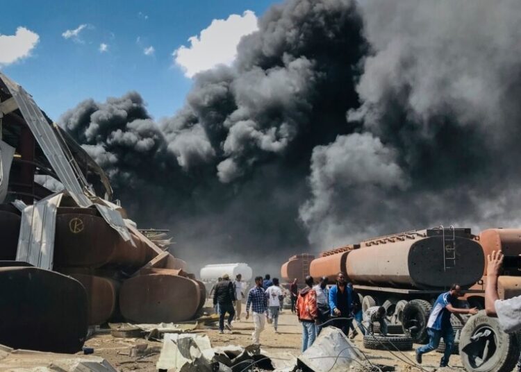 People are seen in front of clouds of black smoke from fires in the aftermath at the scene of an airstrike in Mekele, the capital of the Tigray region of northern Ethiopia, Oct. 20, 2021.