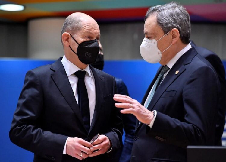 German Chancellor Olaf Scholz, left, speaks with Italy’s Prime Minister Mario Draghi during a round table meeting at an extraordinary EU summit on Ukraine in Brussels, on Feb 24, 2022.