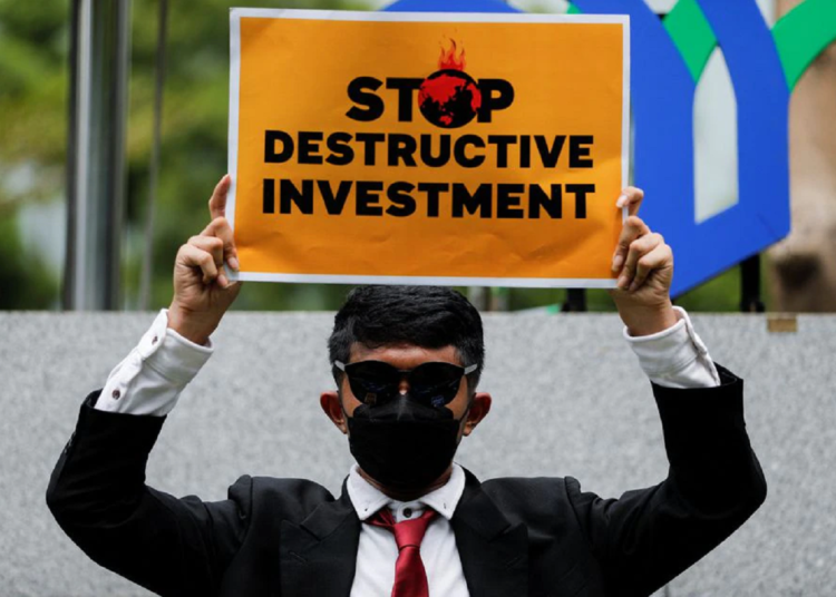 An activist holds a placard while taking part in a rally called "Investment for the Earth, not Oligarchy," asking the government to choose sustainable investment outside the Ministry of Investment's office to mark Earth Day, in Jakarta, Indonesia, April 22, 2022. REUTERS